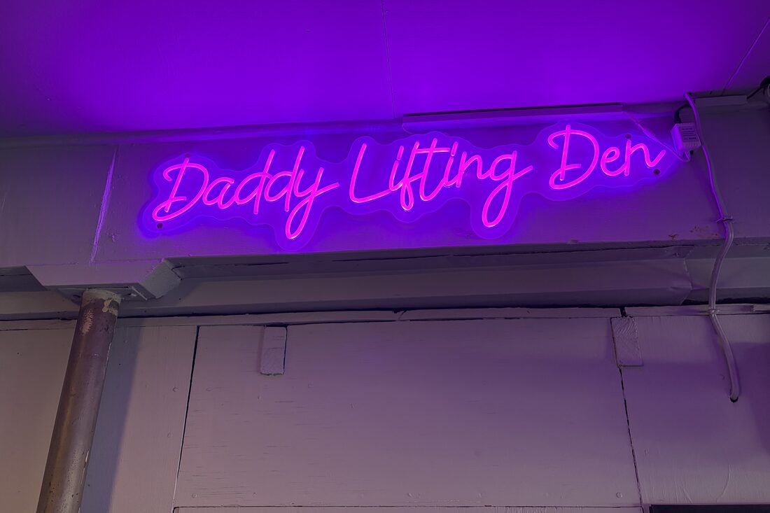 A neon sign reading Daddy Lifting Den