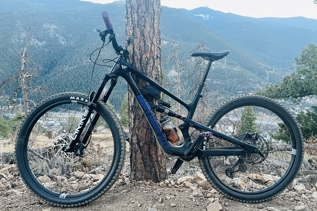 The Shred Sled — a mountain bike on a trail with mountains behind